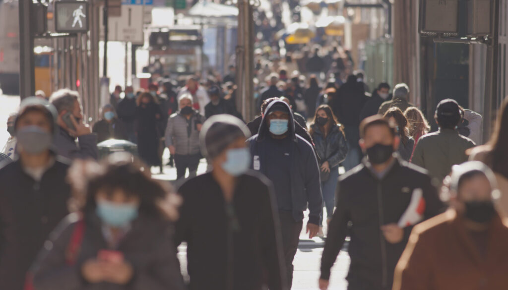 Crowd of people walking street wearing masks